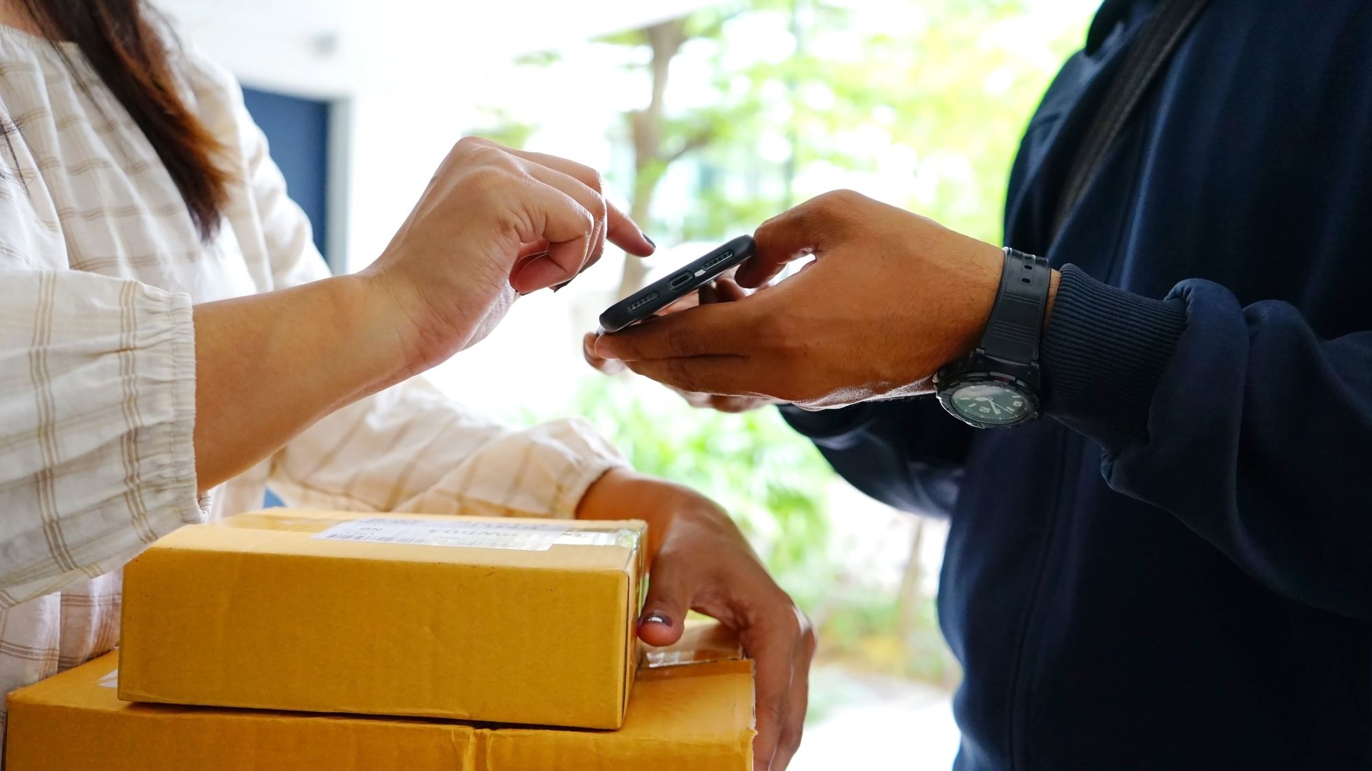A woman signing on a smartphone as proof of delivery for 2 delivered packages